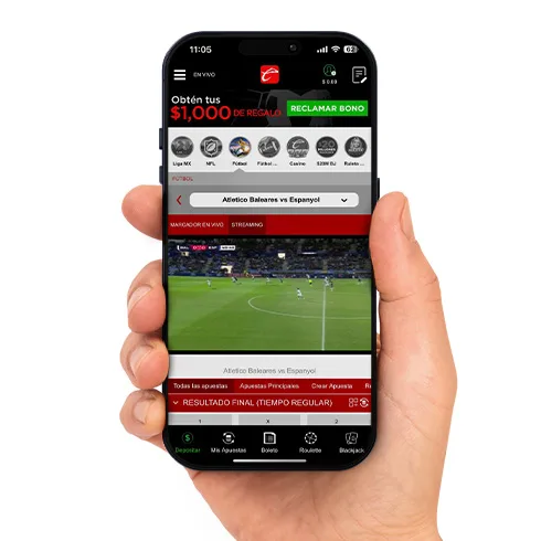 Mano sosteniendo un teléfono con la app de Caliente abierta en un partido con video en vivo, categorías de Liga MX, NFL y fútbol, y un botón de reclamar bono.